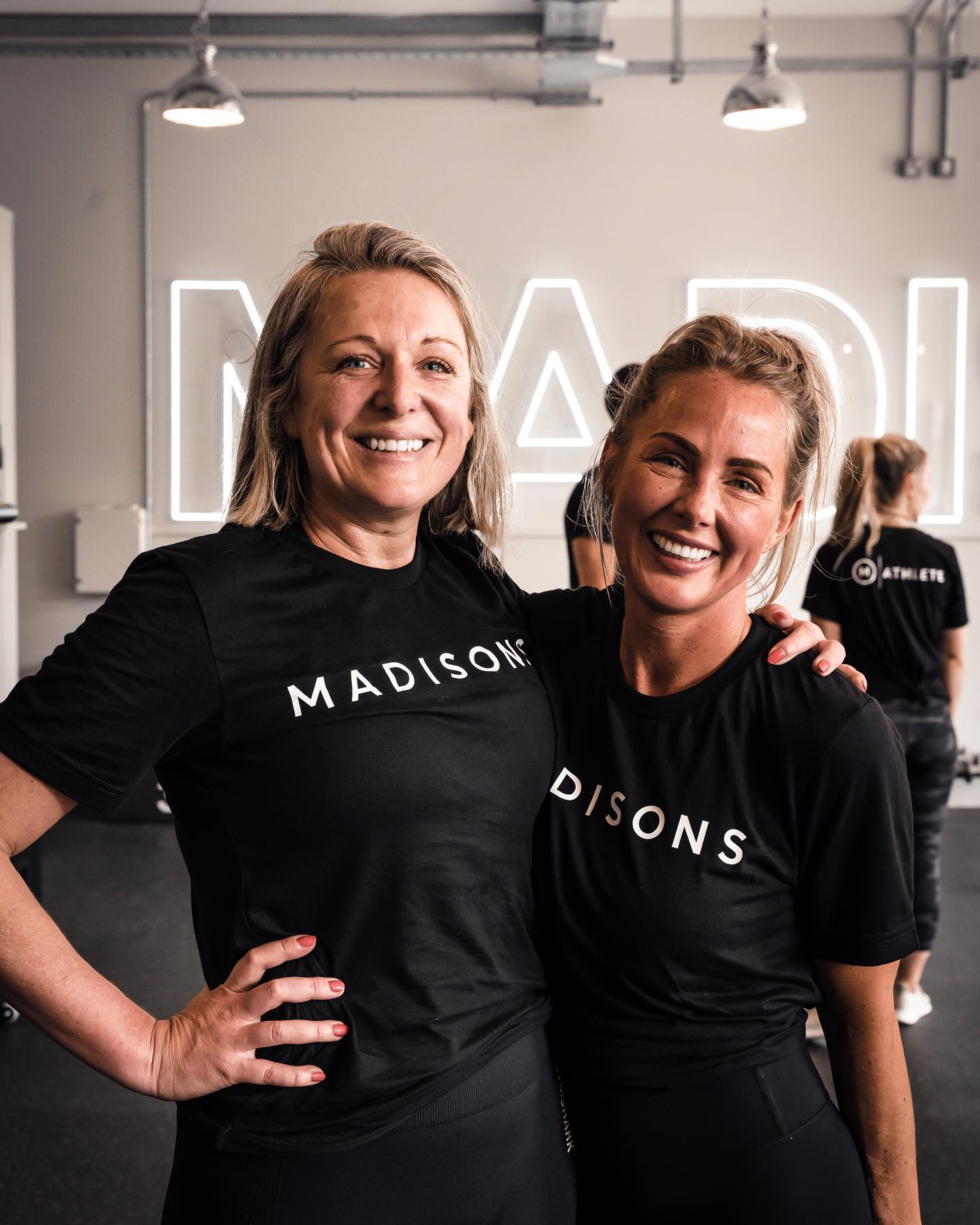 Two people wearing black t-shirts with a Madisons logo looking at the camera and smiling.